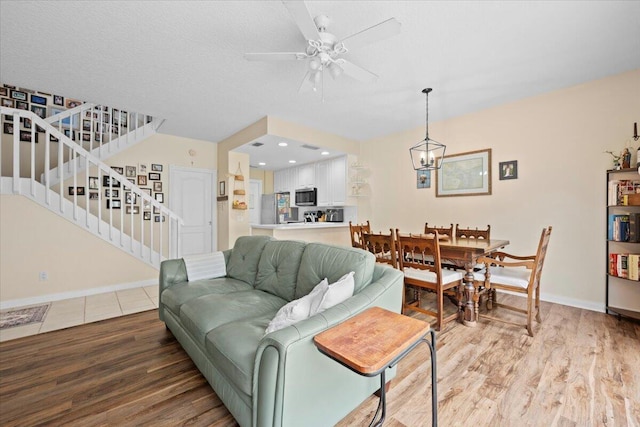 11 Live Oak Cir Unit 11, Tequesta, FL 33469 - living room with stairway, light wood finished floors, a ceiling fan, and a chandelier