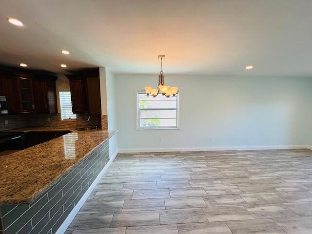 1120 99th St Unit 301, Bay Harbor Islands, FL 33154 - kitchen featuring stone countertops, a chandelier, recessed lighting, backsplash, and stainless steel microwave