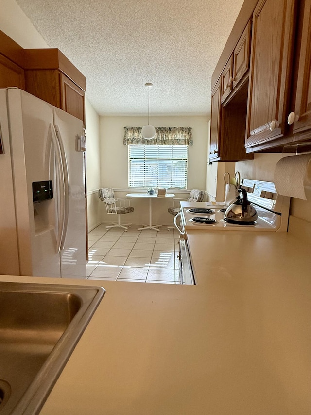 1142 Keystone Dr Unit C, Jupiter, FL 33458 - kitchen with refrigerator with ice dispenser, a textured ceiling, light tile patterned floors, brown cabinetry, and pendant lighting