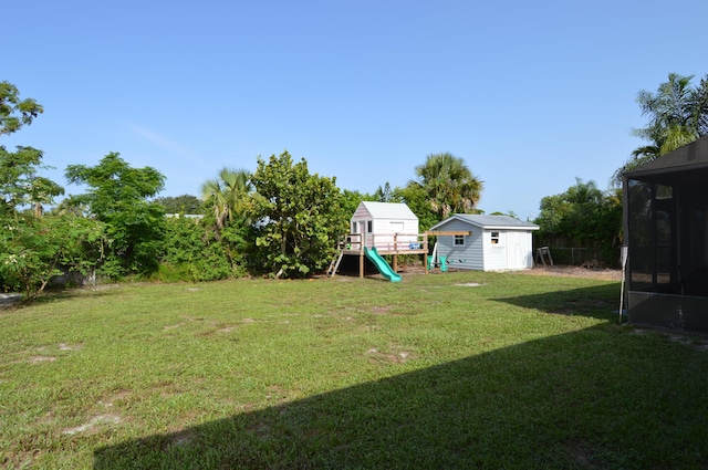 5447 SE 51st Dr, Stuart, FL 34997 - view of grassy yard with a storage unit, a playground, and a sunroom