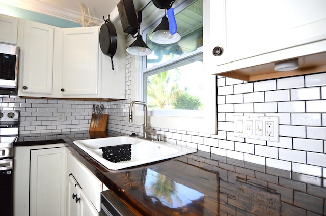 5447 SE 51st Dr, Stuart, FL 34997 - kitchen featuring stainless steel appliances, dark countertops, tasteful backsplash, white cabinets, and crown molding