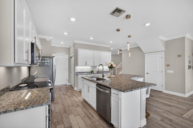 8343 Cinch Way, Lake Worth, FL 33467 - kitchen featuring appliances with stainless steel finishes, light wood-style flooring, ornamental molding, a kitchen island with sink, and white cabinetry