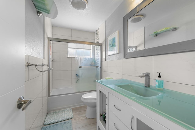 9890 W Heather Ln, Miramar, FL 33025 - bathroom featuring tile walls, vanity, combined bath / shower with glass door, wood finished floors, and a textured ceiling