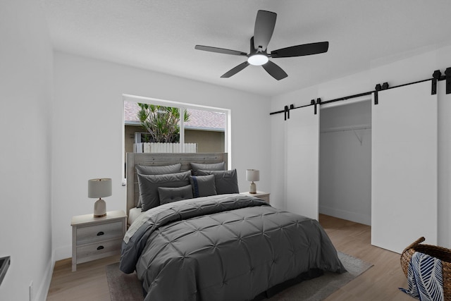 21436 Woodchuck Ln, Boca Raton, FL 33428 - bedroom with a barn door, light wood-style floors, and ceiling fan
