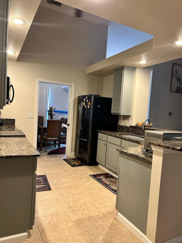 1701 SW Penrose Ave, Port Saint Lucie, FL 34953 - kitchen featuring freestanding refrigerator, gray cabinets, a textured ceiling, dark stone counters, and a peninsula