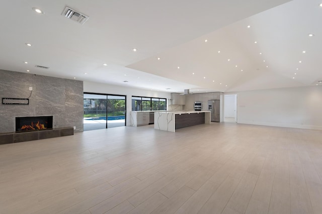 6532 Serena Ln, Boca Raton, FL 33433 - unfurnished living room with recessed lighting, a tile fireplace, vaulted ceiling, and light wood finished floors