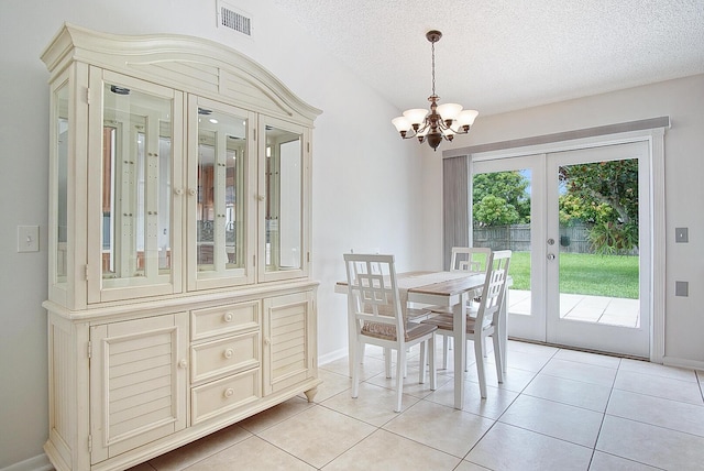 3126 SW Curcuma St, Port Saint Lucie, FL 34953 - dining area with french doors, a chandelier, a textured ceiling, and light tile patterned flooring