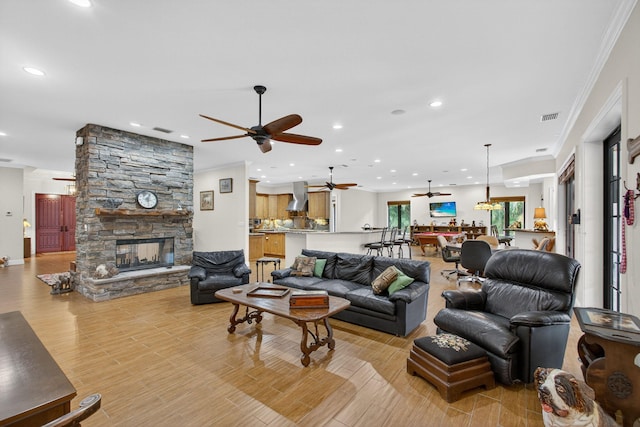 11085 86th St N, Palm Beach Gardens, FL 33412 - living area with a ceiling fan, a stone fireplace, recessed lighting, light wood-style flooring, and ornamental molding
