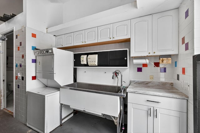 11085 86th St N, Palm Beach Gardens, FL 33412 - kitchen with estacked washer and dryer, concrete flooring, white cabinetry, and light countertops