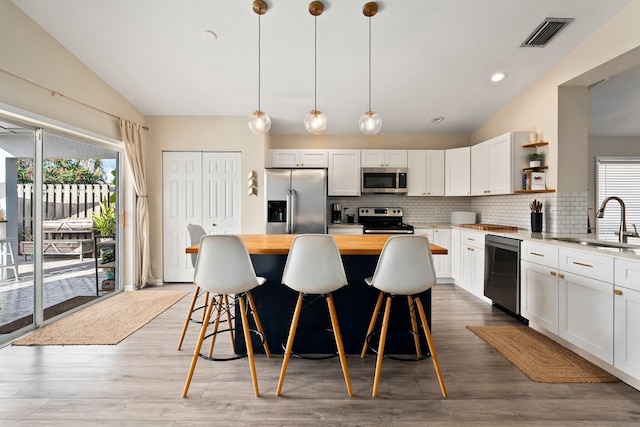 6351 Adams St, Jupiter, FL 33458 - kitchen featuring appliances with stainless steel finishes, vaulted ceiling, wood counters, open shelves, and healthy amount of natural light