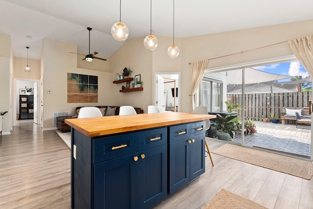 6351 Adams St, Jupiter, FL 33458 - kitchen featuring butcher block counters, blue cabinetry, open floor plan, light wood-style floors, and high vaulted ceiling