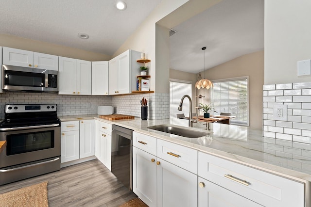 6351 Adams St, Jupiter, FL 33458 - kitchen featuring appliances with stainless steel finishes, lofted ceiling, open shelves, light stone countertops, and white cabinetry
