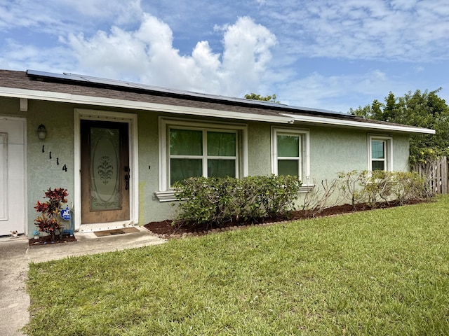 1114 SW Del Rio Blvd, Port Saint Lucie, FL 34953 - view of front of home with stucco siding, solar panels, and a front yard