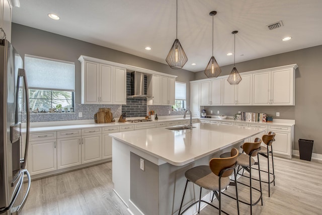 5178 Beckman Ter, Palm Beach Gardens, FL 33418 - kitchen featuring wall chimney exhaust hood, stainless steel appliances, a center island with sink, light wood-style flooring, and recessed lighting