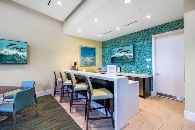 5178 Beckman Ter, Palm Beach Gardens, FL 33418 - kitchen featuring an accent wall, a breakfast bar area, light countertops, wallpapered walls, and recessed lighting