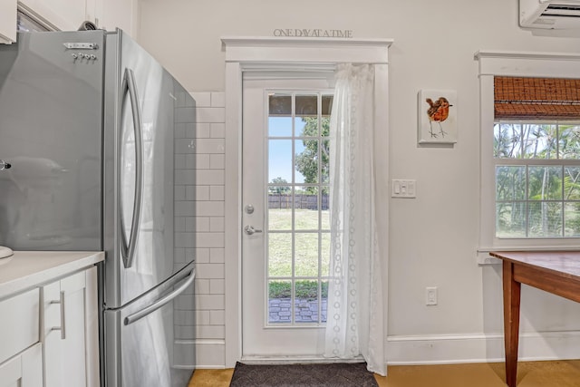 1395 SE Darling St, Stuart, FL 34997 - kitchen with freestanding refrigerator, white cabinetry, a wall mounted AC, and light countertops