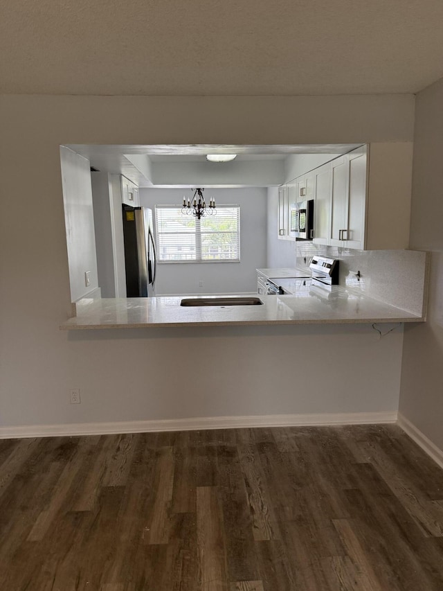 3111 Gardens E Dr Unit 31, Palm Beach Gardens, FL 33410 - kitchen with stainless steel appliances, a chandelier, dark wood finished floors, light countertops, and white cabinets