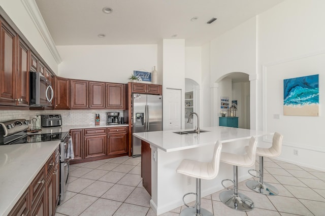 1513 SE Holyrood Ln, Port Saint Lucie, FL 34952 - kitchen featuring appliances with stainless steel finishes, light tile patterned flooring, a breakfast bar area, light countertops, and decorative backsplash
