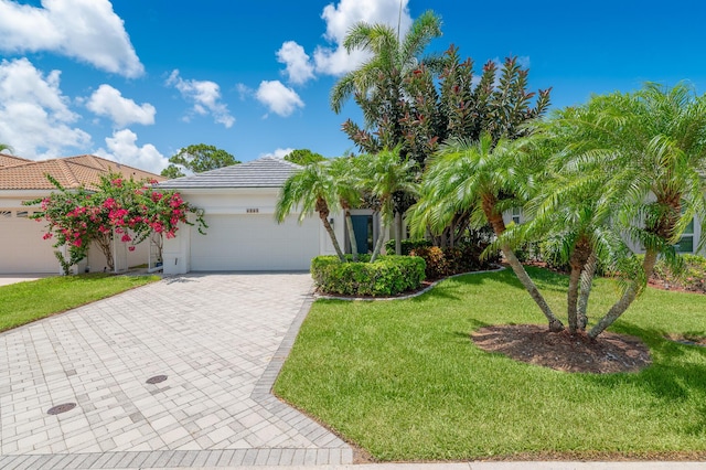 1513 SE Holyrood Ln, Port Saint Lucie, FL 34952 - view of front of home featuring a garage, decorative driveway, a front lawn, stucco siding, and a tile roof