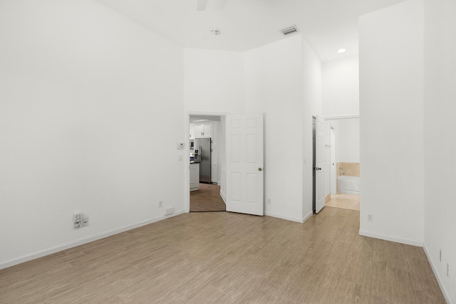 5711 NW 125th Ave, Coral Springs, FL 33076 - unfurnished bedroom with stainless steel fridge with ice dispenser, light wood-style floors, ensuite bath, and a high ceiling