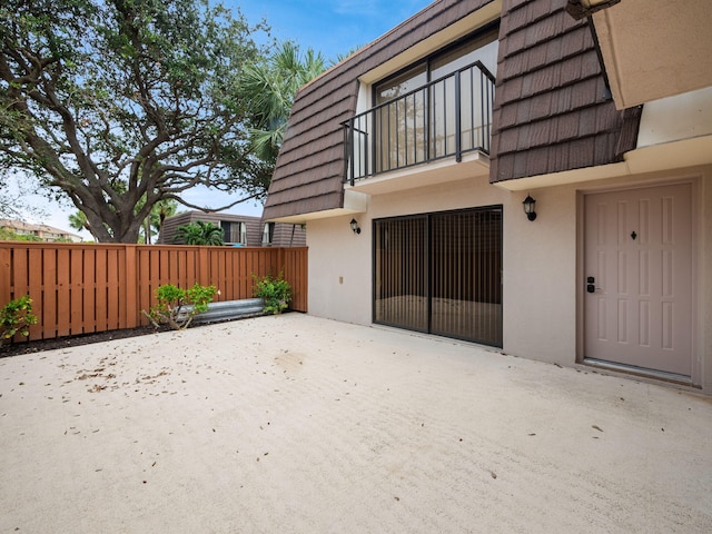 2005 20th Ct, Jupiter, FL 33477 - entrance to property with stucco siding, mansard roof, a patio area, and a balcony