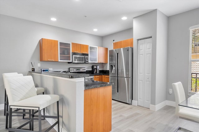 2536 SW 14th Ave Unit 1102, Fort Lauderdale, FL 33315 - kitchen featuring appliances with stainless steel finishes, a peninsula, light wood finished floors, a breakfast bar area, and brown cabinetry