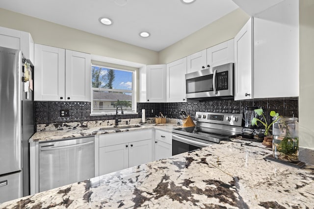 2950 SE Ocean Blvd Unit 119-6, Stuart, FL 34996 - kitchen featuring appliances with stainless steel finishes, light stone counters, white cabinetry, backsplash, and recessed lighting