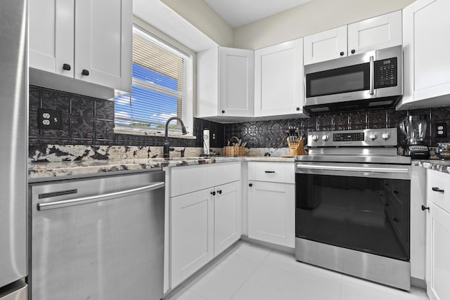 2950 SE Ocean Blvd Unit 119-6, Stuart, FL 34996 - kitchen with stainless steel appliances, stone countertops, tasteful backsplash, white cabinetry, and light tile patterned flooring