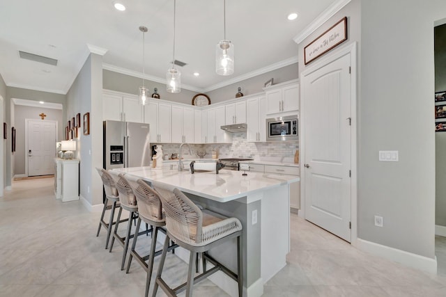 572 SE Villandry Way, Port Saint Lucie, FL 34984 - kitchen with appliances with stainless steel finishes, crown molding, decorative backsplash, white cabinets, and a kitchen bar