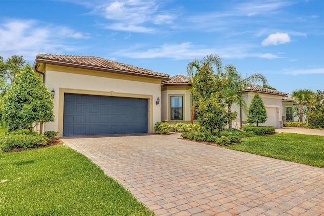 572 SE Villandry Way, Port Saint Lucie, FL 34984 - mediterranean / spanish-style home featuring an attached garage, decorative driveway, a front lawn, stucco siding, and a tiled roof