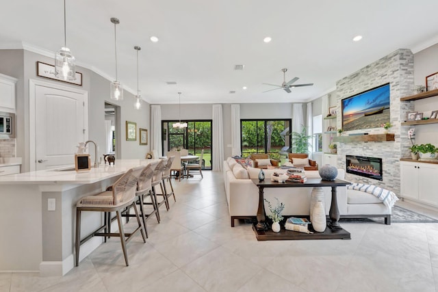 572 SE Villandry Way, Port Saint Lucie, FL 34984 - living area with ornamental molding, a ceiling fan, a large fireplace, recessed lighting, and light tile patterned floors