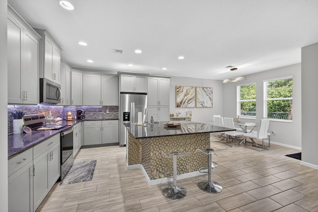 16360 Oakview Dr, Westlake, FL 33470 - kitchen featuring stainless steel appliances, decorative backsplash, a breakfast bar, recessed lighting, and a center island with sink