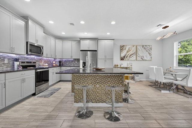 16360 Oakview Dr, Westlake, FL 33470 - kitchen with appliances with stainless steel finishes, recessed lighting, backsplash, a kitchen bar, and a kitchen island with sink