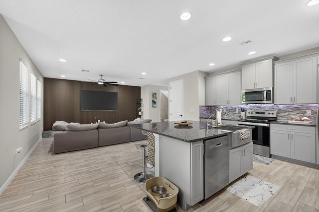 16360 Oakview Dr, Westlake, FL 33470 - kitchen featuring appliances with stainless steel finishes, an island with sink, ceiling fan, open floor plan, and light wood-style flooring