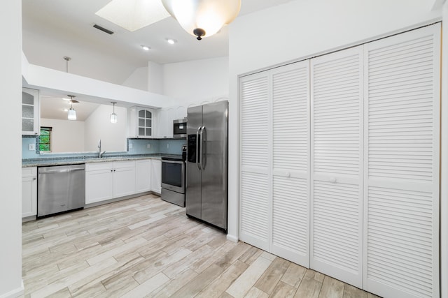 9904 Summerbrook Ter Unit C, Boynton Beach, FL 33437 - kitchen with appliances with stainless steel finishes, a skylight, glass insert cabinets, lofted ceiling, and light wood-style flooring