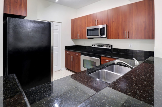 4903 Midtown Ln Unit 3120, Palm Beach Gardens, FL 33418 - kitchen featuring appliances with stainless steel finishes, dark stone counters, light tile patterned floors, and brown cabinetry