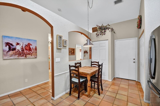 9484 Swansea Ln, West Palm Beach, FL 33411 - dining area with arched walkways, light tile patterned flooring, and a textured wall