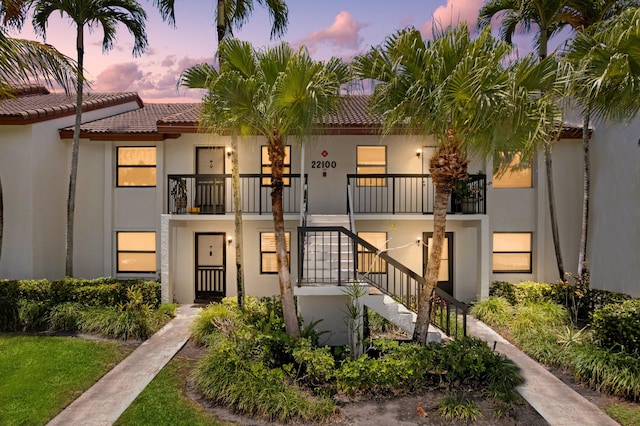 22100 Palms Way Unit 204, Boca Raton, FL 33433 - view of property featuring stucco siding, a tiled roof, a balcony, and stairs