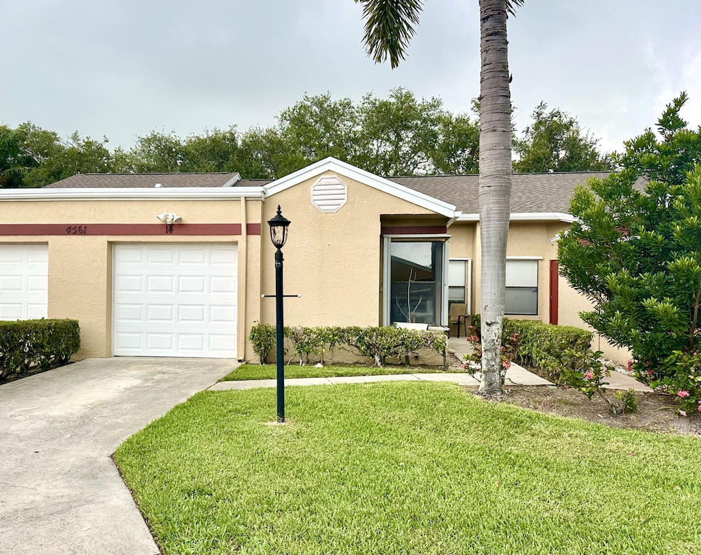 4561 Discovery Ln Unit 14, West Palm Beach, FL 33417 - view of front of home featuring driveway, a front lawn, stucco siding, and an attached garage