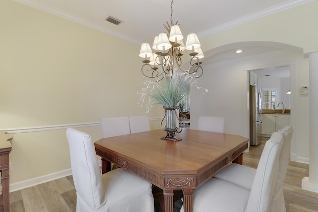 2000 SW Oakwater Pt, Palm City, FL 34990 - dining room featuring arched walkways, a chandelier, light wood-style floors, and ornamental molding