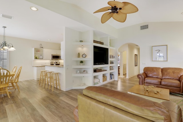 2000 SW Oakwater Pt, Palm City, FL 34990 - living room with arched walkways, ceiling fan, light wood-style floors, lofted ceiling, and a chandelier