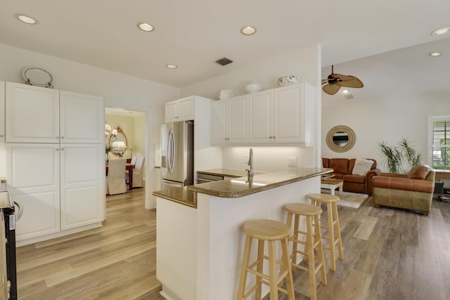 2000 SW Oakwater Pt, Palm City, FL 34990 - kitchen with stainless steel fridge, light wood-style flooring, a kitchen breakfast bar, ceiling fan, and recessed lighting