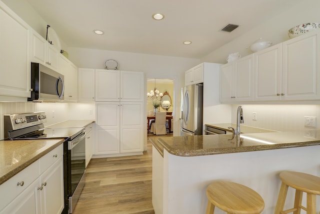 2000 SW Oakwater Pt, Palm City, FL 34990 - kitchen featuring appliances with stainless steel finishes, a breakfast bar, light wood-style flooring, white cabinets, and a peninsula