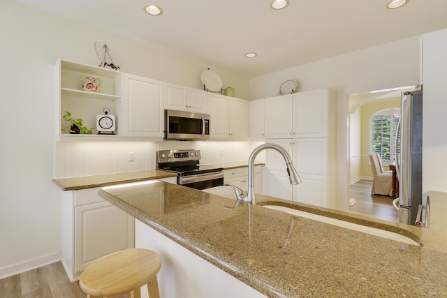 2000 SW Oakwater Pt, Palm City, FL 34990 - kitchen with appliances with stainless steel finishes, light stone countertops, white cabinets, recessed lighting, and light wood finished floors