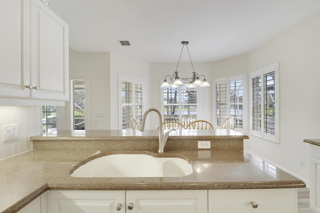 2000 SW Oakwater Pt, Palm City, FL 34990 - kitchen with dark stone counters, pendant lighting, white cabinetry, a chandelier, and a peninsula
