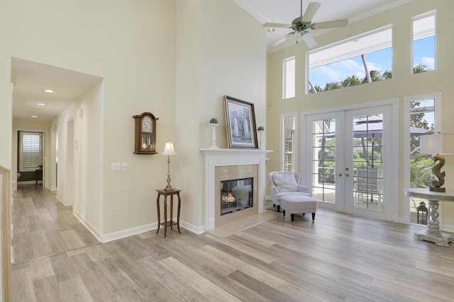 2000 SW Oakwater Pt, Palm City, FL 34990 - sitting room with light wood-style floors, a high ceiling, a tiled fireplace, a ceiling fan, and french doors