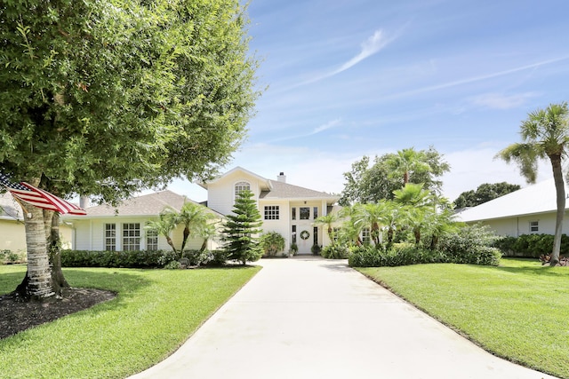 2000 SW Oakwater Pt, Palm City, FL 34990 - view of front facade with a front lawn, concrete driveway, a chimney, and a shingled roof