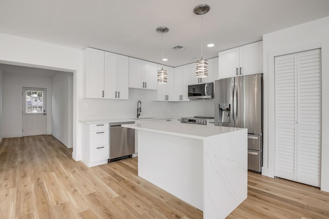 701 37th St, West Palm Beach, FL 33407 - kitchen with stainless steel appliances, light countertops, a center island, white cabinetry, and pendant lighting