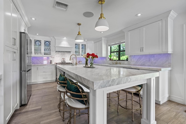 6204 Celadon Cir, Palm Beach Gardens, FL 33418 - kitchen with stainless steel appliances, white cabinets, a kitchen breakfast bar, a center island with sink, and recessed lighting
