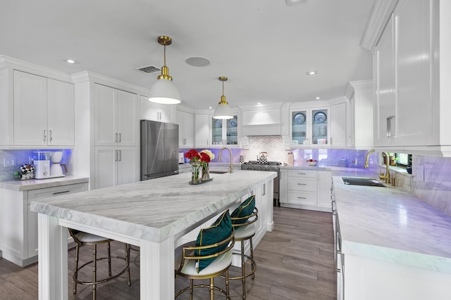 6204 Celadon Cir, Palm Beach Gardens, FL 33418 - kitchen featuring appliances with stainless steel finishes, backsplash, white cabinets, a kitchen bar, and recessed lighting